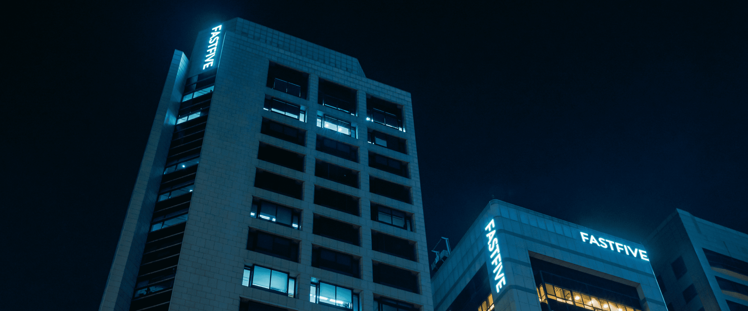 늦은 밤 사무실에 불이 켜져 있는 fastfive 빌딩